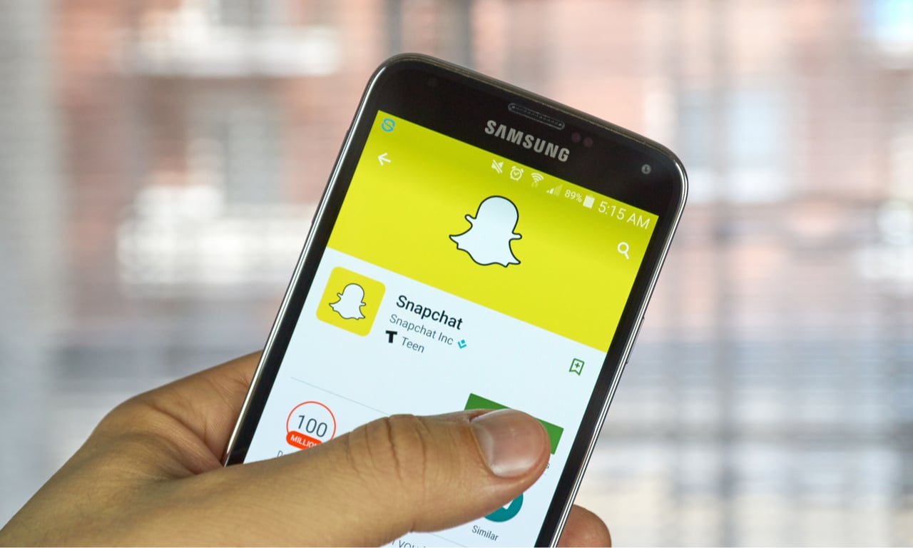 someone holdng a smartphone pressing the download button to get the snapchat app